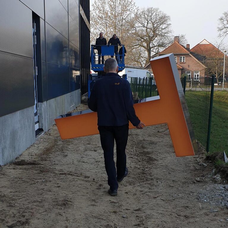 jank_werbetechnik_dlm_02 Mann trägt Leuchtbuchstaben zur Montage